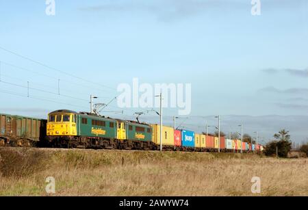 Ein Paar Elektrolokomotiven der Klasse 86 mit den Nummern 86639 und 86628 mit Doppelüberschrift und Freightliner fahren bei Mark Tey auf der Great Eastern Mainline. Stockfoto