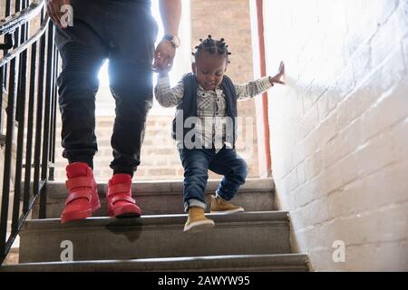 Vater hilft Kleinkindsohn, Treppen hinabzusteigen Stockfoto