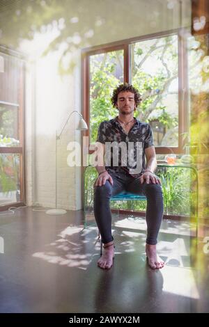 Heiterer junger Mann meditiert im Heimbüro Stockfoto