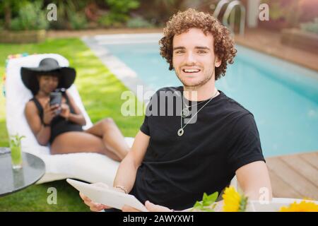 Portrait fröhlicher junger Mann mit digitalem Tablet am Pool Stockfoto