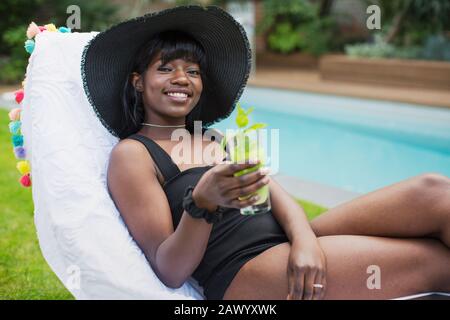 Portrait schöne junge Frau entspannend mit Cocktail am Pool Stockfoto