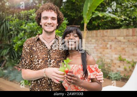 Portrait fröhliches multiethnisches Paar, das Cocktails auf der Terrasse trinkt Stockfoto