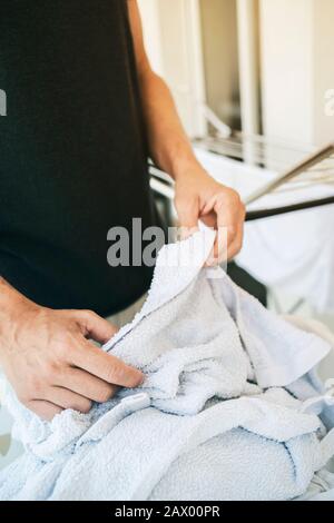 Nahaufnahme eines jungen kaukasischen Mann hängen nasse Kleidung auf einem Wäscheständer in einen Balkon Stockfoto