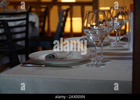 Selektive Fokusaufnahme von Essgeschirr und einem Weinglas In einem Esstisch eines Restaurants angeordnet Stockfoto