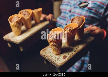 Wafer mit Schokoladenfüllung auf einem Holzteller Waffelhörner mit Hüttenkäse werden mit Schokolade bestreut Stockfoto