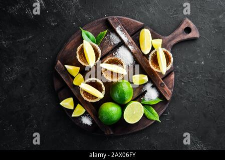 Goldtequila mit Kalk und Salz auf schwarzem Steingrund. Draufsicht. Freier Speicherplatz für Ihren Text. Stockfoto