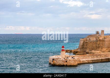 Red Old Lighthouse im Grand Harbour und der Wellenbrücke, Fort Ricasoli aus Valletta auf Malta, Insel des Mittelmeers Stockfoto