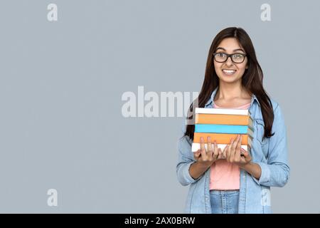 Junges indisches Studenten-Mädchen, das Bücher in Händen hält Stockfoto