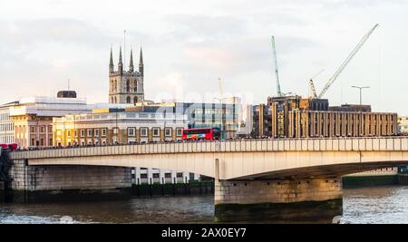 Pendler, die über die London Bridge laufen, mit einem roten Routenmeister, der vorbeikommt Stockfoto