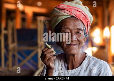 Alte glückliche Dame der Ethnischen Minderheit Der Pa'O, die eine birmanische Zigarre raucht und im Dorf Indein in der Nähe von Inle Lake, Shan State, Myanmar (Birma) lächelt. Stockfoto