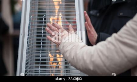 Frau verwärmte die Hände vor einer Gasheizung Stockfoto