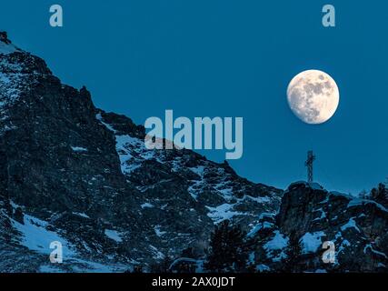 Italien Valle D'Aosta Val di Rhemes - Der fast Vollmond steigt am Abend über den Kamm des Val di Rhemes. Stockfoto