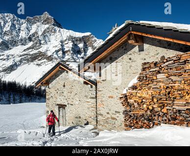 Italien Valle D'Aosta Val di Rhemes - Auf den Almen des Entrelor, einer kleinen Gruppe von Häusern und Ställen, die von Schnee bedeckt sind. Im Hintergrund steht die Grande Rousse. Stockfoto