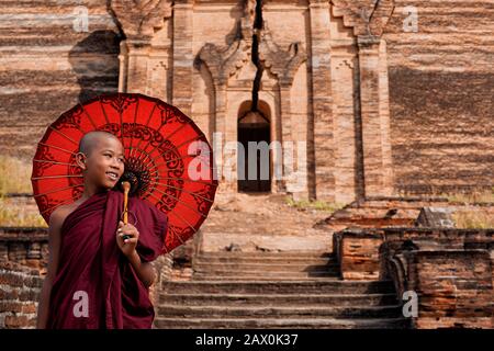 Mandalay, Myanmar (Birma), ein glücklicher buddhistischer Mönch für Anfänger, der sich auf den Ruinen der Mingun Pahtodawgyi Pagode befindet. Stockfoto