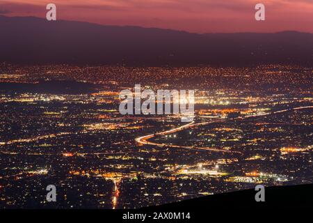 Panorama-Nachtblick über die Ausbreitung der Stadt in San Jose, Silicon Valley, Kalifornien; Sichtbarer Lichtpfad links von Autos, die auf einer der Autobahnen fahren; Long ex Stockfoto