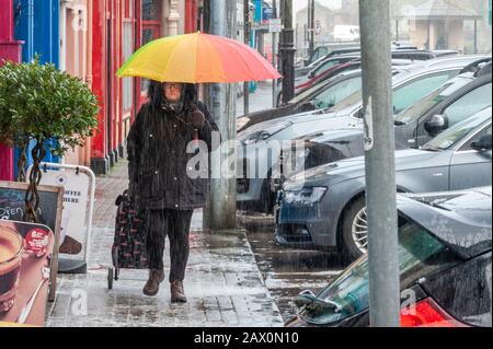 Bantry, West Cork, Irland. Februar 2020. Eine Frau geht durch Bantry Stadt in dem Versuch während des Donner, Blitz und Hagel Sturm, der die Stromversorgung der Stadt für eine kurze Zeit heute zu versagen verursacht. Kredit: AG Nachrichten/Alamy Live Nachrichten Stockfoto