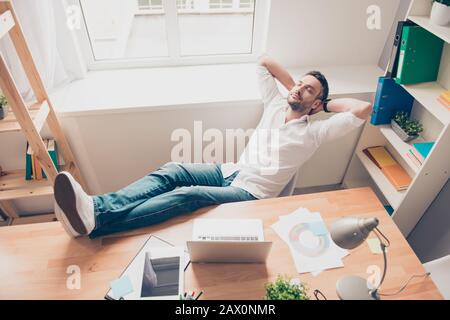 Entspannter glücklicher Mann schläft und hält Beine auf dem Tisch Stockfoto