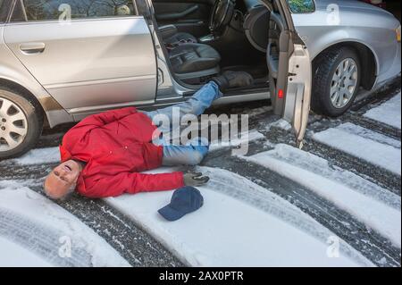 Der ältere Mann rutschte auf Eis, das aus seinem Auto kam Stockfoto