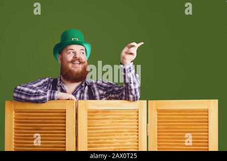 Happy St. Patricks Day. Fetter komischer bärtiger Mann hat einen Finger auf den grünen Patrick's Tageshintergrund Stockfoto