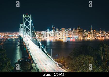 Klassischer Panoramablick auf die Skyline von San Francisco mit der Oakland Bay Bridge, die in der Abenddämmerung im Sommer in Kalifornien, USA, beleuchtet wird Stockfoto