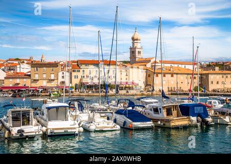 Klassischer Panoramablick auf die berühmte Skyline von Krk mit Segelbooten, die im Sommer im historischen hafengebiet der mittelmeer-insel ankern, Kroatien Stockfoto