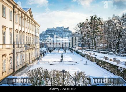 Klassischer Blick auf die berühmten Mirabell-Gärten in der historischen Stadt Salzburg mit der Festung Hohensalzburg an einem schönen schneebedeckten Winterabend, Österreich Stockfoto