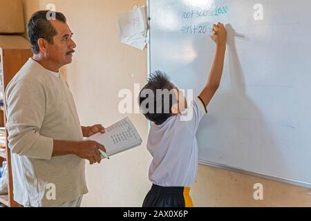Brisas de Zicatela, Oaxaca, Mexiko - EIN Lehrer beobachtet, wie ein Schüler in einer dritten Klasse an der Escuela Primaria Tierra y Liberdad, einer PRI, ein Mathematikproblem macht Stockfoto