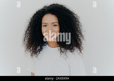 Konzept für Glück, Wohlbefinden und positive Emotionen. Kopfschuss der sympathisch aussehenden Dame mit knackigen Haaren, Lächeln und Lachen, hat eine gesunde Haut, trägt Casu Stockfoto
