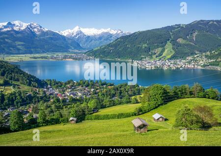 Panoramasicht auf die schöne Landschaft in den Alpen mit Bergsee und Wiesen mit alten Chalets im Frühjahr, Zell am See, Salzburger Land, Österreich Stockfoto