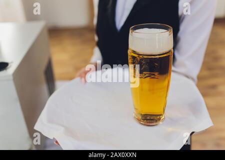 Bedienung Hand und Tablett mit Bier ins Glas Stockfoto