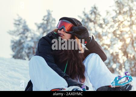 Stock-Foto eines jungen Snowboarders, das auf dem Schnee des Berges sitzt Stockfoto