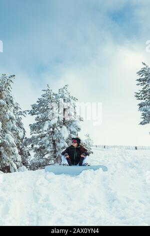 Stock-Foto eines jungen Snowboarders, das auf dem Schnee des Berges sitzt Stockfoto