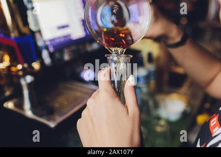 Barkeeper gießt Whisky-Glasflaschen, die in einer Reihe stehen Stockfoto