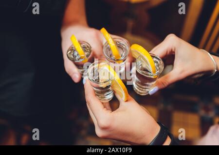 Toasten mit Freunden shot Gläser über einen alten Holztisch schwarzen Hintergrund Stockfoto