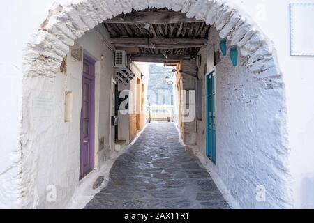 Traditionelle griechische weiß getünchte Gebäude, Kopfsteinpflasterstraßen und Steinstrukturbogen im Dorf Ioulida, Chora. Stockfoto