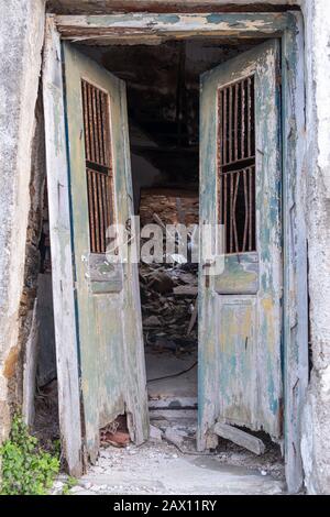 Alte und zerstörte doppelte offene Tür. Aus Holz, geschälte, freigeschaltete Tür in einem verlassenen und zerstörten Haus. Einsturzgefahr, vertikale Sicht. Stockfoto