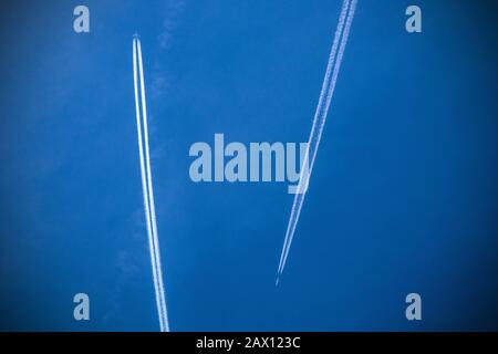 Zwei Flugzeuge, die in Reiseflughöhe in einem blauen Himmel vom Boden aus über London, England, vorbeifliegen Stockfoto