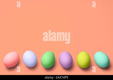 Eierreihe mit verschiedenen Farben unten auf pinkfarbenem Hintergrund mit Copyspace. Frohe ostern Stockfoto