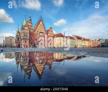 Wroclaw, Polen. Historisches Rathausgebäude - das architektonische Wahrzeichen der Stadt, das sich in Pfütze auf dem Rynek Platz widerspiegelt Stockfoto