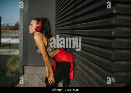 Die hübsche junge Frau macht eine Pause, nachdem sie im Stadtgebiet gelaufen ist Stockfoto