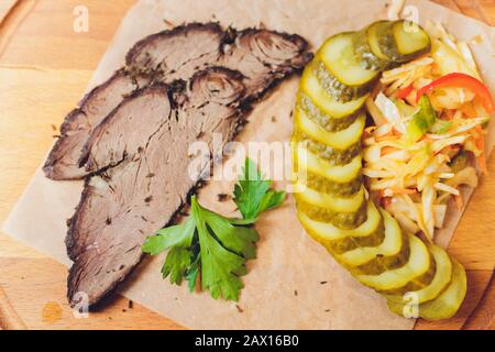 Lebensmittelzusammensetzung mit Roastbeef Salat mit sonnengetrockneten Tomaten. Arugula, Tomate und Gurke auf weißem Teller auf grauem Hintergrund. Draufsicht Stockfoto