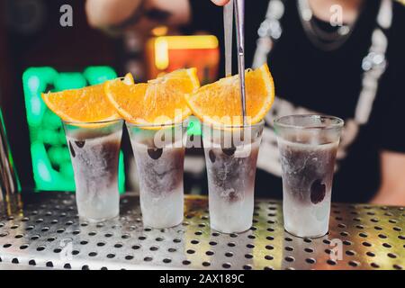 Barkeeper gießen stark alkoholisches Getränk in kleinen Gläsern auf Bar, Schüsse Stockfoto