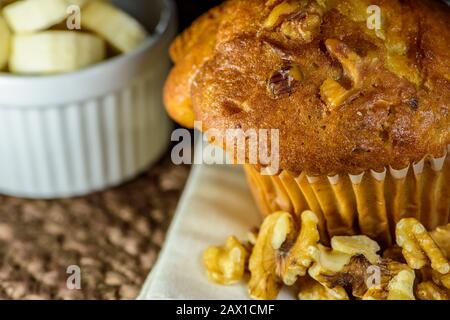 Frischer Bananennussmuffin, umgeben von Walnüssen und geschnittenen Bananen. Stockfoto