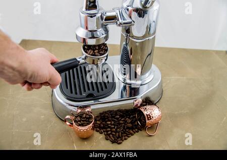 Frisch gerösteter Kaffee in Espresso-Arbeit. Bei der Zubereitung von Kaffee. Espresso-Kaffeemaschine im Retro-Stil. Kaffeebohnen und Metallbecher. Kaffee ist ein guter Sta Stockfoto