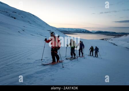 Eine Gruppe von Skifahrern beim Sonnenaufgang in Island mit Wasser dahinter Stockfoto