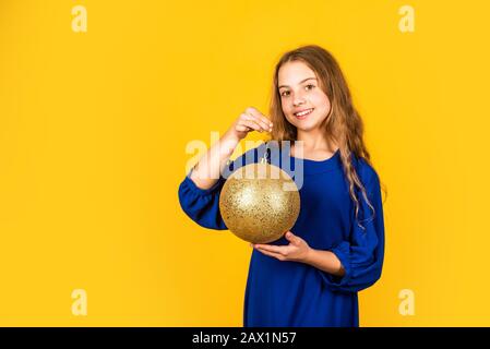 Bereiten Sie die Dekorationen im Voraus vor. Mädchen halten goldene Kugeldekorationen für weihnachtsbaum. Dekoratives Accessoire Shop. Überprüfen Sie die Weihnachtsdekorationen. Gold Stockfoto