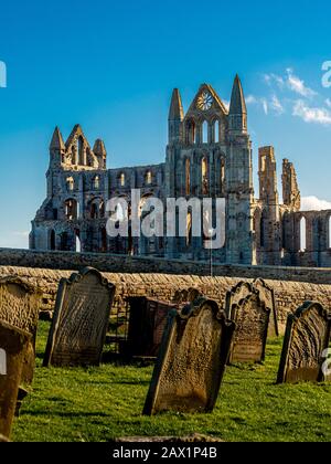 Grabsteine auf dem Friedhof der St Marys Church mit Whitby Abbey im Hintergrund, Whitby, Großbritannien. Stockfoto