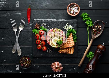 Beef Steak Tatar mit rohem Eigelb, Avocado, Kapern und Zwiebeln. Französische Küche. Draufsicht. Freier Speicherplatz für Ihren Text. Stockfoto