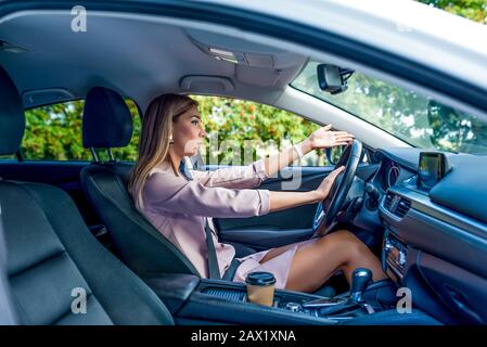 Frau im Auto, Hupensignal, Unfall und Unfall auf der Straße, Handgeste. Negative Reaktion, scharfe Kritik, Stau, schlechte Autofahrt Stockfoto