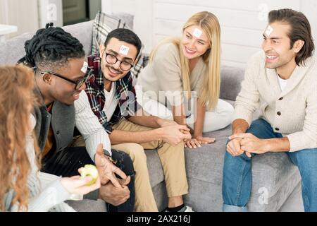 Eine Gruppe glücklicher Freunde, die zusammen sitzen, um auf dem Sofa zu spielen, Um Zu Raten, Welches Spiel, ein High Angle Shot, gespielt hat Stockfoto